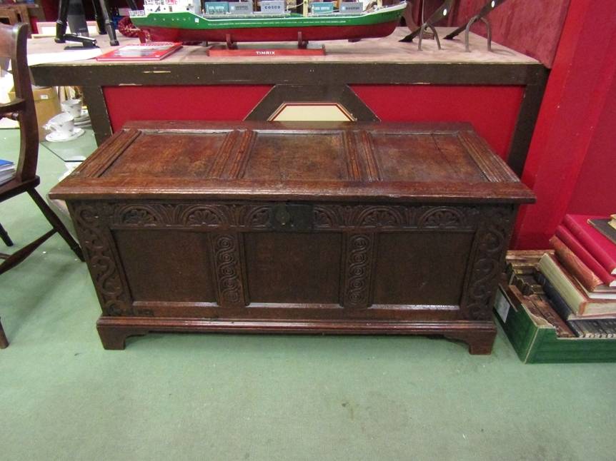 A 17th Century and later oak three panel coffer the split hinged rising top over a carved front on