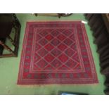 A square rug with diamond geometric patterned centre on red ground with tasselled ends, 125 x 125cm