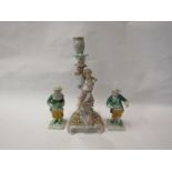 A German porcelain figural candlestick, floral encrusted, boy smelling flower, crossed mark to base.