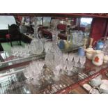 A crystal glass decanter with grape and vine detail and a selection of liquer glasses