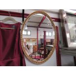 An oval gilt framed bevel edged wall mirror