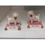 A pair of Staffordshire style poodle figures stood on cushions