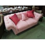 A modern pink button back scroll arm cottage sofa with loose seat cushions and three decorative