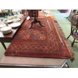 A red ground rug of geometric design with multiple borders and tasselled ends, a/f, torn, 170cm x