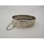 A silver engraved stiff hinged bangle