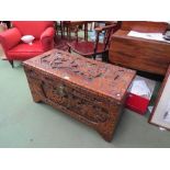 An Eastern carved camphor wood linen chest, decorated with battle scenes and floral/foliate borders.