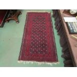 A wool rug with red ground, multiple borders, tasselled ends, 188cm x 96cm
