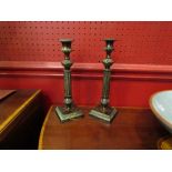 A pair of cast metal column form candlesticks, 17cm tall