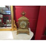 An early 20th Century ornate brass mantel clock with urn finial and twin handles, painted enamel