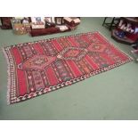 A large Kilim tribal rug, geometric borders, three central lozenges, tasselled ends, 315cm x