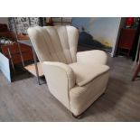 A 1940's Danish armchair, clam shell back in original ivory coloured upholstery, raised on dark