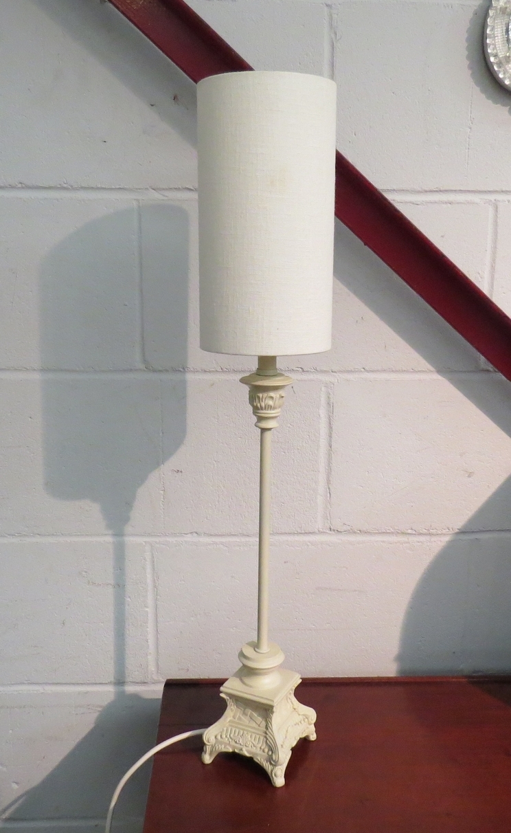 A slender table lamp with cream base and shade