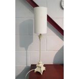 A slender table lamp with cream base and shade