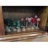 A collection of coloured glass: cranberry example, cut glass, green glass, mainly wine glasses