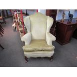 A Queen Anne style hump back winged fireside armchair, the scroll arms and feather filled cushion