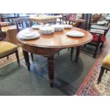 A circa 1840 mahogany library table, the drop-leaf circular top over two frieze bow front end