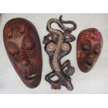 Two carved wooden wall hanging masks painted in tribal style decoration, together with a carved