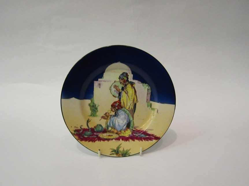 A B.P. Co Ltd Omar Khayyam plate depicting a snake charmer with onlooker, 18.5cm diameter