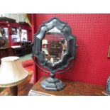 A table mirror with crackled black paintwork and shaped frame