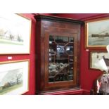 A Georgian flame mahogany corner cabinet with glazed door and shaped shelved interior with key, 86cm