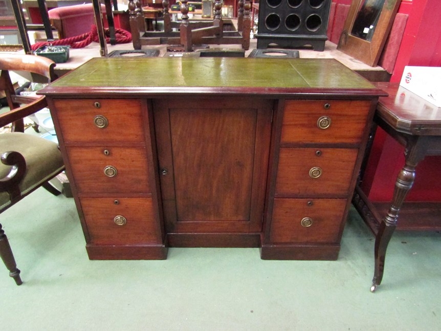 Circa 1860 a mahogany breakfront desk, the gilt tooled leather inset writing surface over six