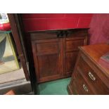 An Arts & Crafts oak two door wall cupboard with working lock and key (formerly housed a dartboard)