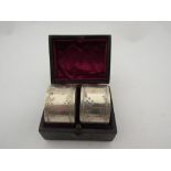 A cased set of two silver napkin rings in tooled leather case