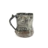 An Abuja Pottery tankard, ash grey glaze over an incised detailed body. 'ABUJA' and E.T. impressed