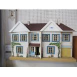 A 1950's Tri-ang two storey dolls house with garage, furnished with vintage plastic furniture