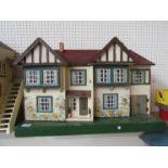 A Tri-ang two storey dolls house with garage, containing assorted vintage dolls house furniture (