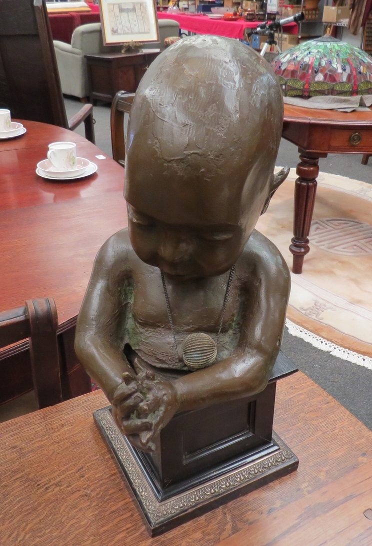 A bronzed resin sculpture on plinth of a small child. Overall height 43cm