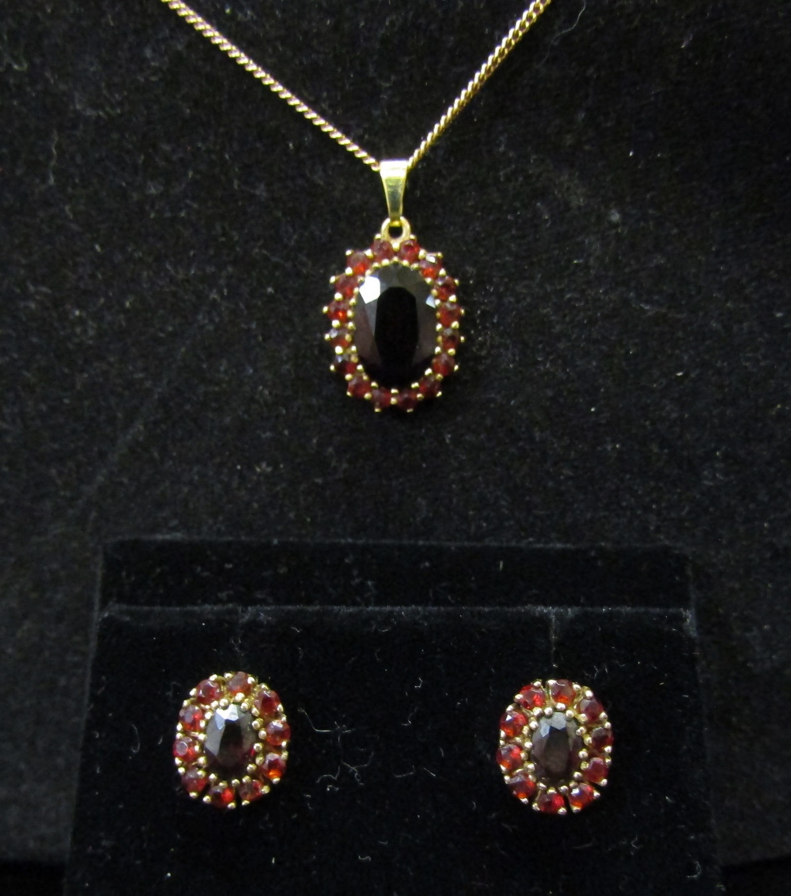 A 9ct gold garnet cluster pendant hung on 9ct gold chain, with a pair of matching earrings, 7.6g