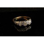 A gold platinum set three stone diamond ring in heart shaped illusion setting, marks rubbed. Size L,