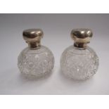 A pair of silver topped globular scent bottles, hinge broken on one