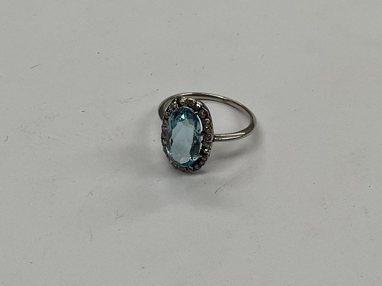 An aquamarine and diamond ring, the oval aqua 12mm x 7mm, framed by small diamonds in unmarked white