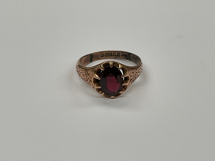 A 9ct gold engraved ring with oval garnet set in claw mount, repaired, size P, 3.9g