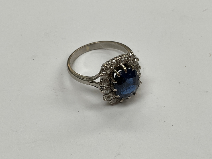 A sapphire and diamond ring, the central sapphire 9mm x 7mm, framed by 16 round cut diamonds,