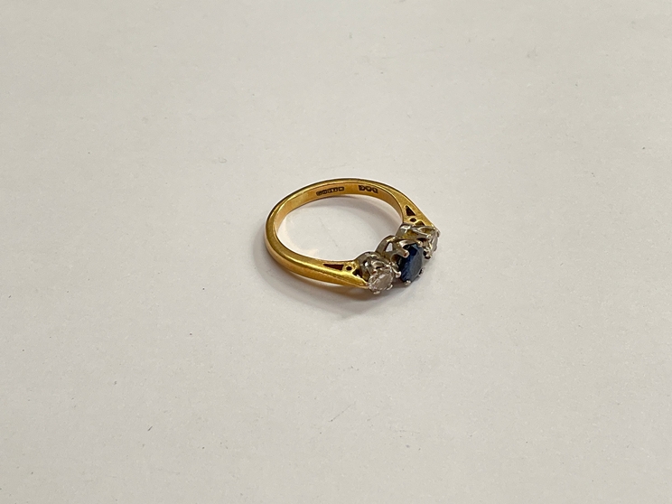 An 18ct gold sapphire and diamond ring, the central blue sapphire flanked by 0.20ct diamonds. Size