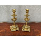 A pair of 19th Century brass candlesticks in the Baroque style, urn support, on dolphin supports,