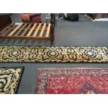 A Chinese black wool runner rug with gold decoration, 372cm x 77cm