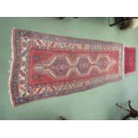 Two wool rugs, red ground, geometric design, multiple borders