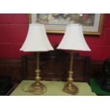 A pair of decorative gilt table lamps with cream shades