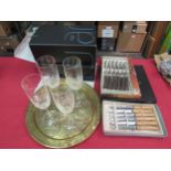 A brass circular tray, boxed cutlery sets including steak knives and four Stuart crystal flute