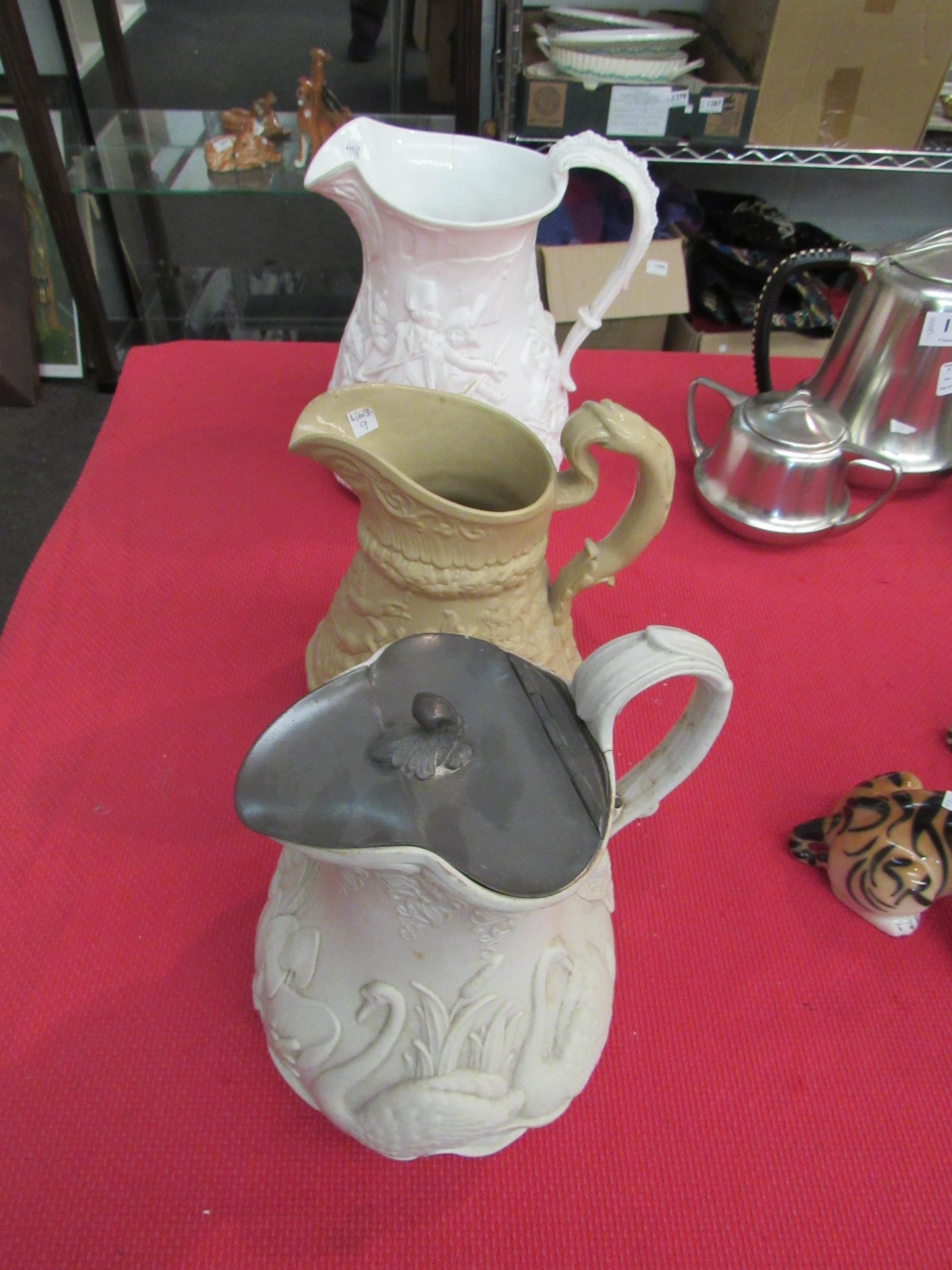 Three Victorian moulded jugs: The Battle of Acre a/f, Minton decorated with swans, with pewter lid