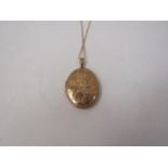 A 9ct gold oval engraved locket hung on 9ct gold chain 5.9g