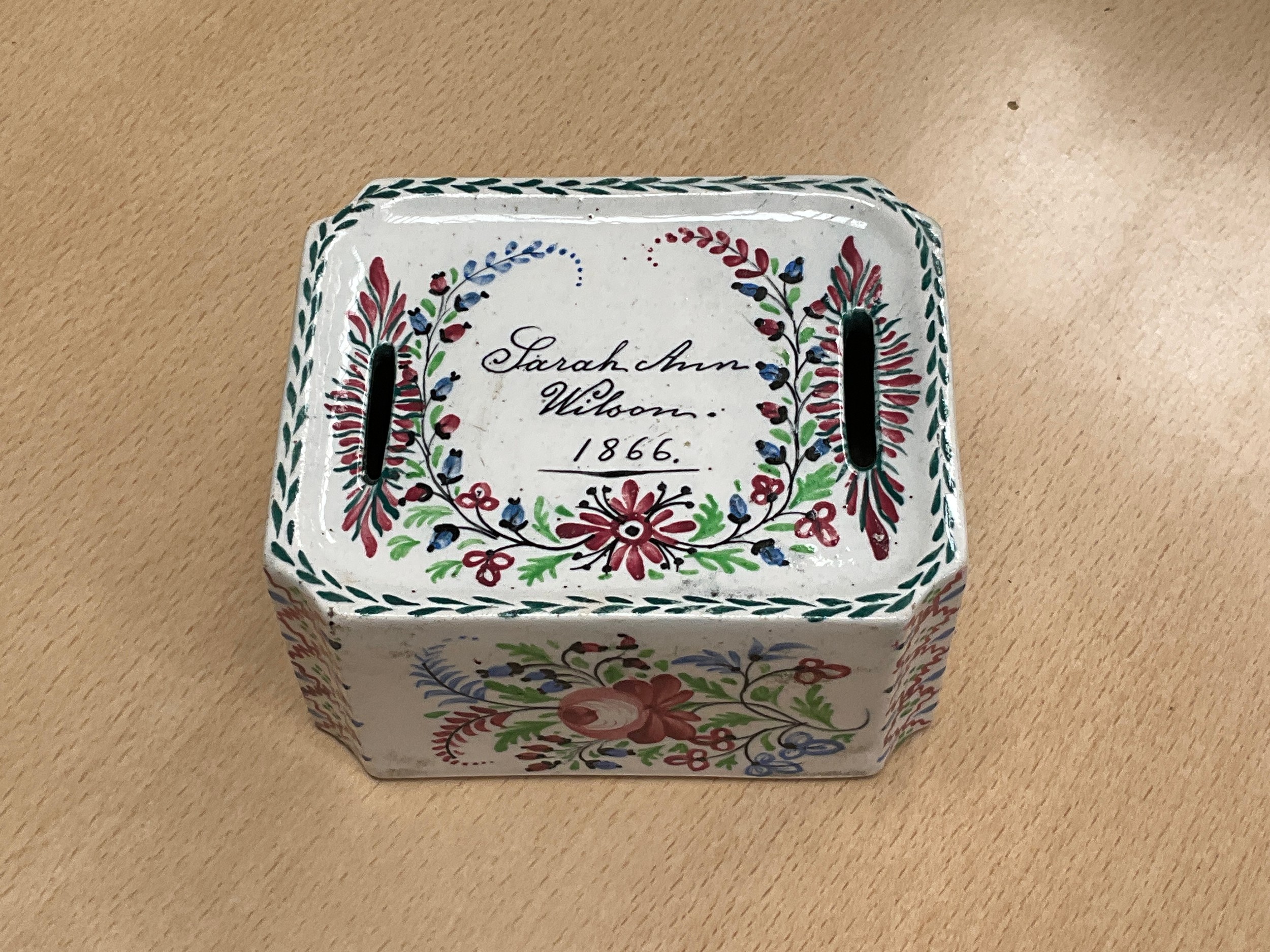 A Victorian ceramic money box, hand painted canted rectangular form, twin slots, Sarah Ann Wilson