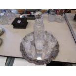 A crystal glass decanter and seven glasses on a plated tray