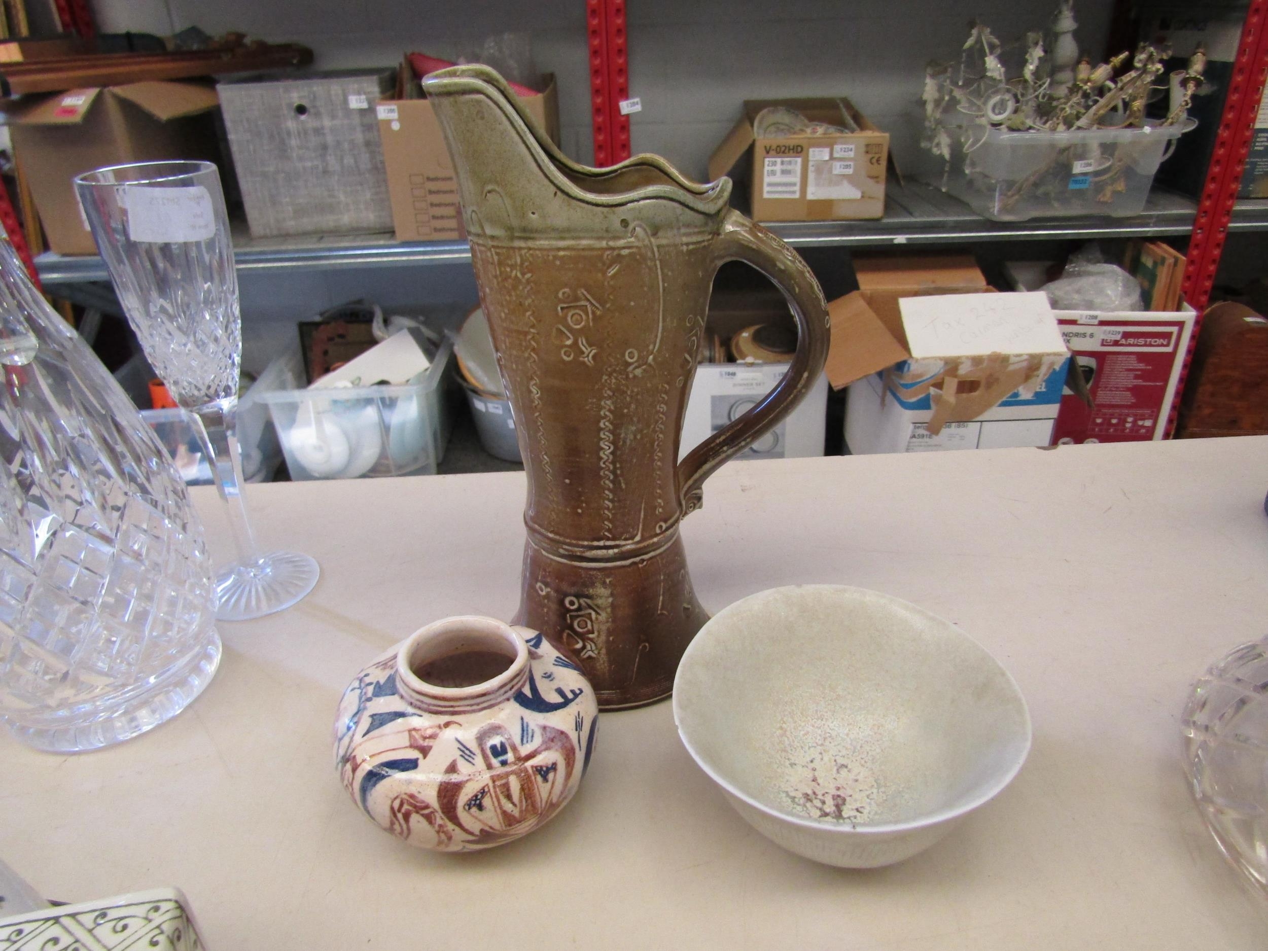 A studio pottery jug with incised decoration and owl detail at base of handle, seal mark to side,