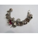 A silver bracelet hung with various charms including windmill, horse and jockey, squeeze box, swan