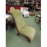 A circa 1840 button back walnut slipper chair with carved acanthus leaf decoration on white